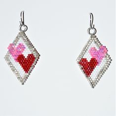 a pair of earrings with red and pink hearts on them, hanging from silver hooks