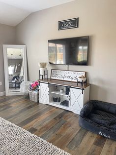 a living room with a dog bed and television on top of the entertainment center in it