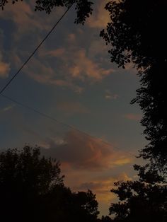 the sun is setting behind some trees and power lines