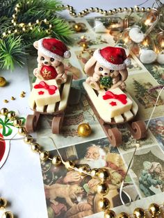 two small figurines sitting on top of a table next to christmas decorations and ornaments