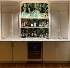 a kitchen with white cabinets and shelves filled with liquor bottles on top of it's counter tops