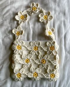 a crocheted purse with yellow and white flowers on it sitting on a bed