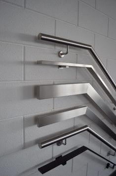 three metal shelves on the side of a white brick wall with bars attached to them