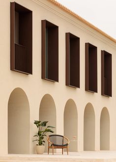 a chair sitting in front of a building with arched windows and shutters on the side