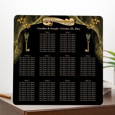 a black and gold wedding seating chart on a wooden table next to a potted plant