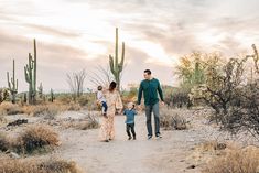 a family walking in the desert with cactus trees and cacti behind them at sunset