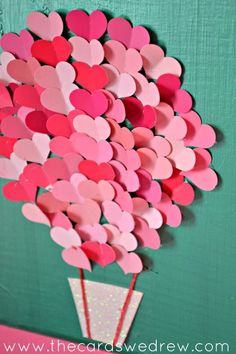 a vase filled with lots of hearts on top of a green table next to a wall