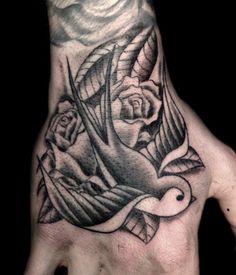 a hand with a bird and roses tattoo on it