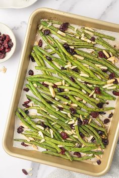 cooked green beans and cranberries in a baking dish with almonds on the side