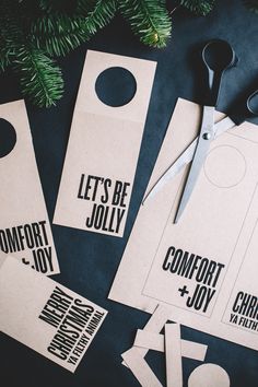 some scissors are laying next to some tags on a table that says, let's be jollyy comfort and joy