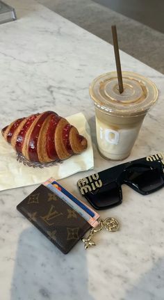 some food and sunglasses on a table next to a cup of coffee with a straw