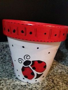 a red and white pot with ladybugs painted on it