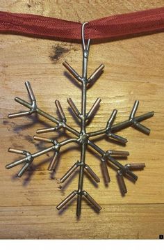 a snowflake ornament hanging from a red ribbon on a wooden table