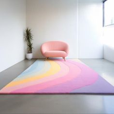 a pink chair sitting on top of a rug next to a potted plant in a white room