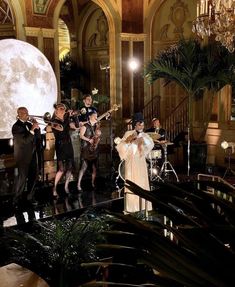 a group of people standing on top of a stage next to a giant full moon