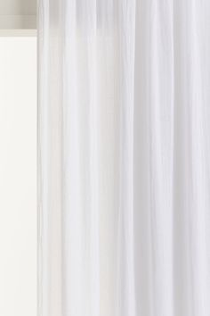 a white curtain hanging on the side of a window