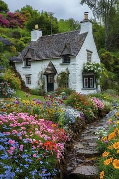 a white house surrounded by colorful flowers and greenery