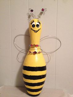 a yellow and black striped vase sitting on top of a white tablecloth covered floor