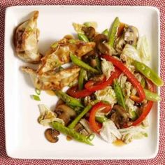 a white plate topped with meat and veggies on top of a red table cloth