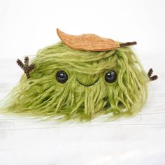 a green stuffed animal with a leaf on top of it's head and eyes