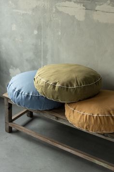 three round pillows sitting on top of a wooden bench