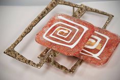 two red and white square shaped rings on a silver ring holder with an intricate design