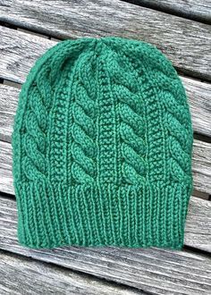 a green knitted hat sitting on top of a wooden bench