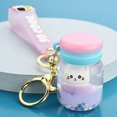 a keychain with a cat in a jar on it and a pink toothbrush next to it