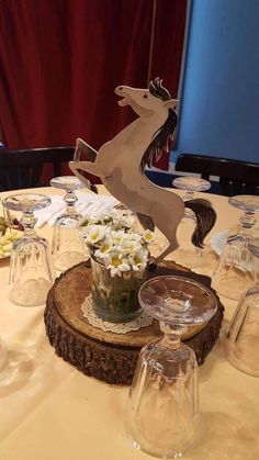 a table topped with glass vases filled with white flowers and a wooden horse figurine