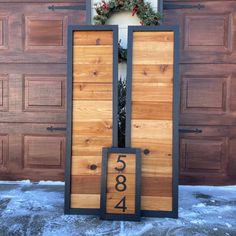 a wooden door with numbers on it in front of a house that is decorated for christmas