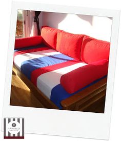 a red, white and blue couch sitting in front of a window