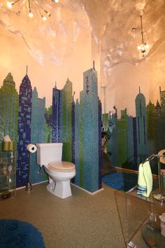 a bathroom decorated in blue and green with cityscape on the wall behind the toilet