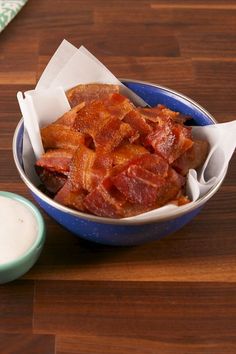 a bowl filled with bacon sitting on top of a wooden table