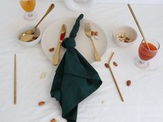 a white table topped with plates and silverware next to bowls filled with food on top of it