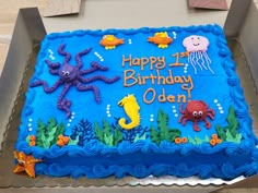 a birthday cake with blue frosting and under the sea decorations on it's side