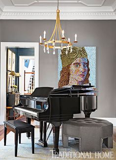 a grand piano and ottoman in a living room with a chandelier hanging from the ceiling