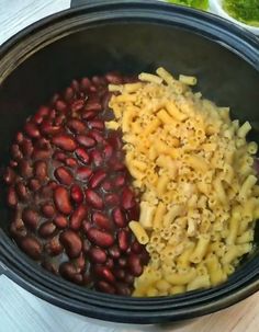 three different types of pasta in a black bowl on a wooden table with other food items