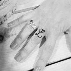 a woman's hand with a small bow tattoo on her left thumb and the word love written in black ink