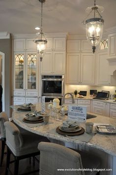 a large kitchen with white cabinets and marble counter tops, along with an island in the middle