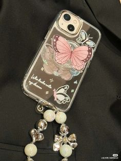 an iphone case with a butterfly and beads attached to the back of it, on a black background