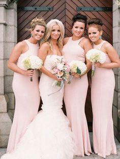 a group of women standing next to each other in front of a door wearing dresses