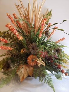 a vase filled with lots of different types of flowers and leaves on top of a table