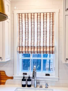 a kitchen sink under a window next to a faucet