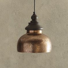 a copper colored pendant light hanging from a ceiling