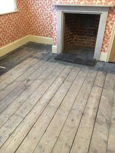 an empty room with wood floors and a fireplace