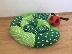 a green and white dog bed with a ladybug on it