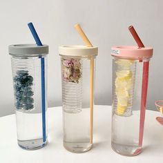 three plastic cups with straws and drinks in them on a white countertop next to pictures