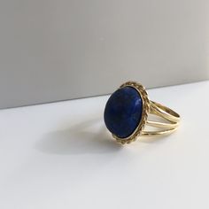 Lapis lazuli - richly blue and in excellent shape. This massive lapis is held in a beautiful vintage ring crafted in 18K yellow gold with beautiful braided bezel detail. The shank splits in three different bands tapering down to a single band at the bottom of 4.30mm This ring is currently a size 8.5 but can be sized down upon request. With any pre-owned/Vintage/Antique items, it is common to have some wear, As we inspect each piece of our jewelry, we make sure the wear and tear is acceptable wit Timeless Blue Oval Cabochon Jewelry, Timeless Blue Gemstone Signet Ring, Elegant Blue Oval Cabochon Signet Ring, Blue Cabochon Sapphire Ring In 14k Gold, Elegant Blue Gemstone Signet Ring, Elegant Blue Sapphire Signet Ring, Fine Jewelry Blue Lapis Lazuli Ring, Blue Lapis Lazuli Signet Ring With Gemstone, Blue Lapis Lazuli Rings Fine Jewelry