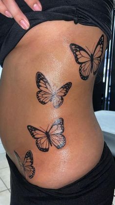 a woman's stomach with butterflies painted on the side and behind her belly, in front of a tiled floor