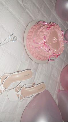 a pink cake and shoes on a table with balloons in the shape of people's feet